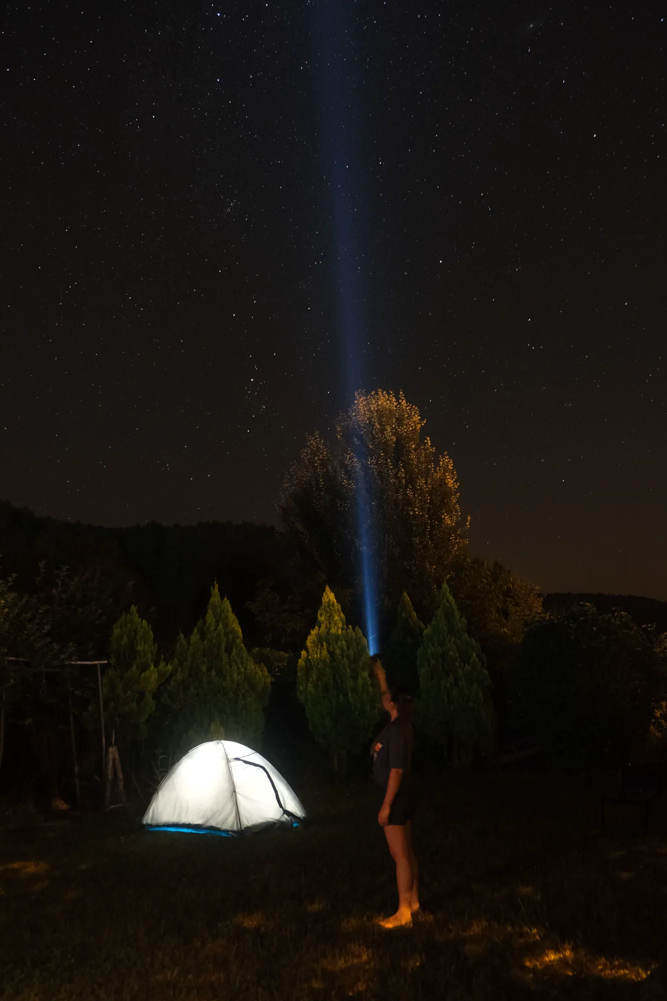 夜間營地中有人以手電筒照向星空