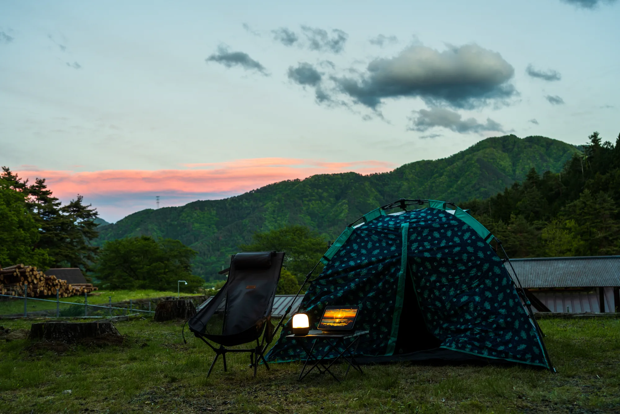山間夕陽下的帳篷、營燈與筆電