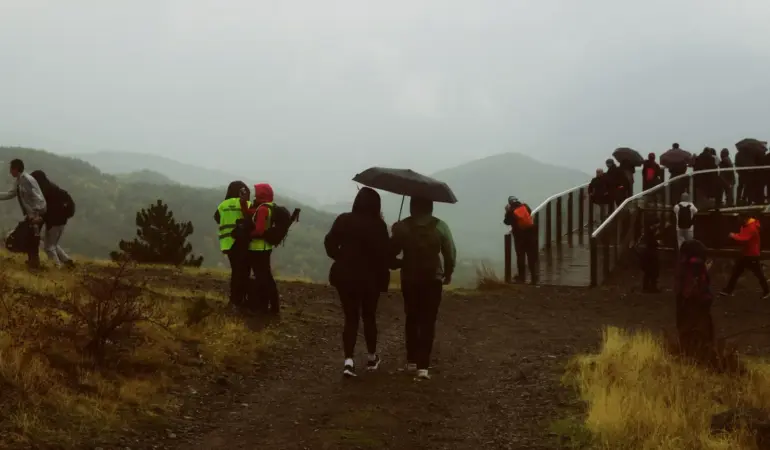 一群健行者在山區雨天撐傘行走。