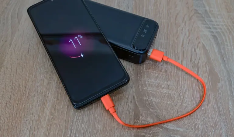 手機以橘色充電線連接桌上的行動電源