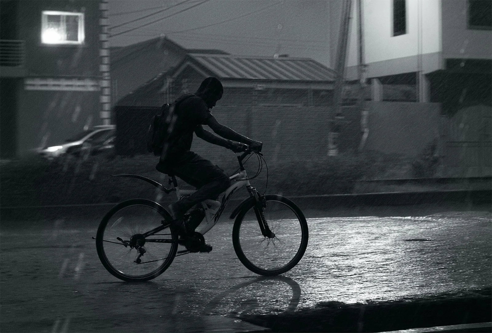 夜雨中騎自行車的騎士與車燈