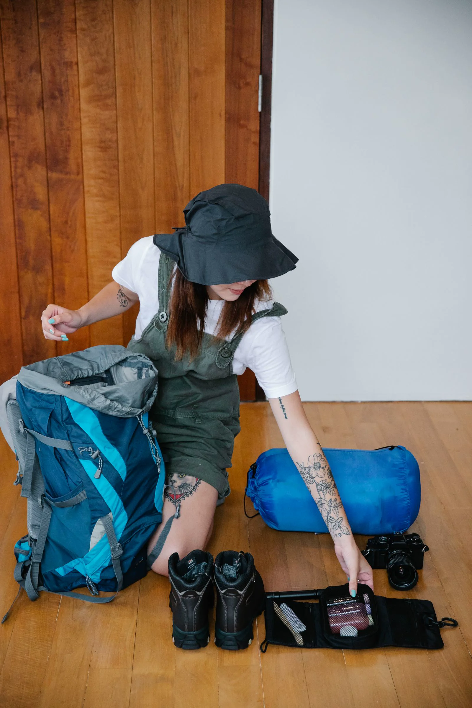 出發前整理戶外用品 女子把登山鞋與衣物等裝備整理在背包旁。