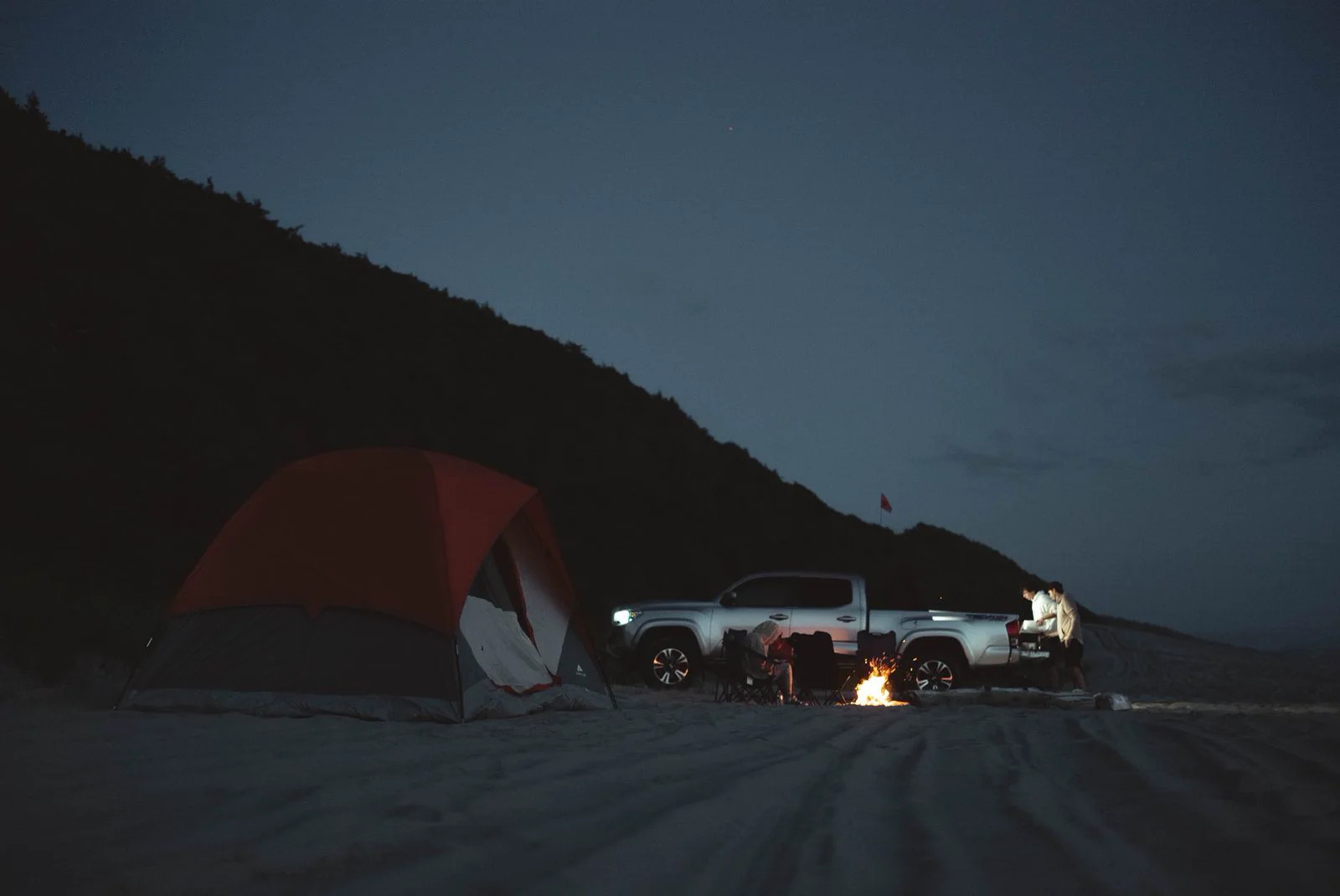 夜色中的帳篷和車輛停在海岸營地。