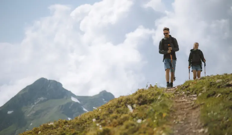 兩名健行者在山徑上使用登山杖行走